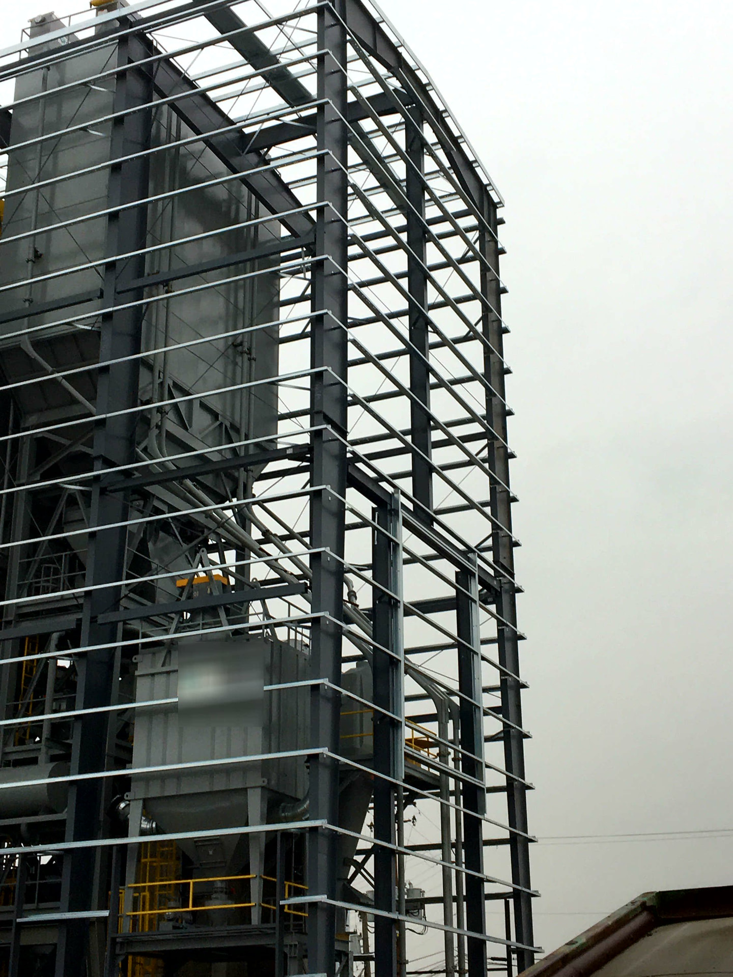 Multi-story structural steel frame surrounding industrial silos and process equipment