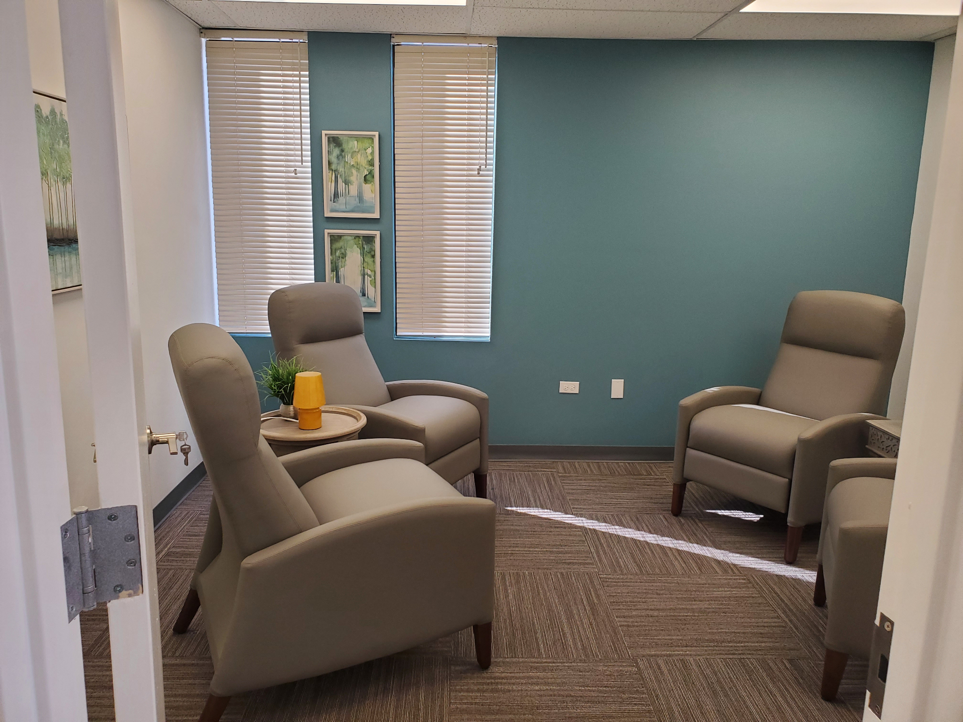 Lounge room with recliners, a small side table, teal accent wall, and window blinds