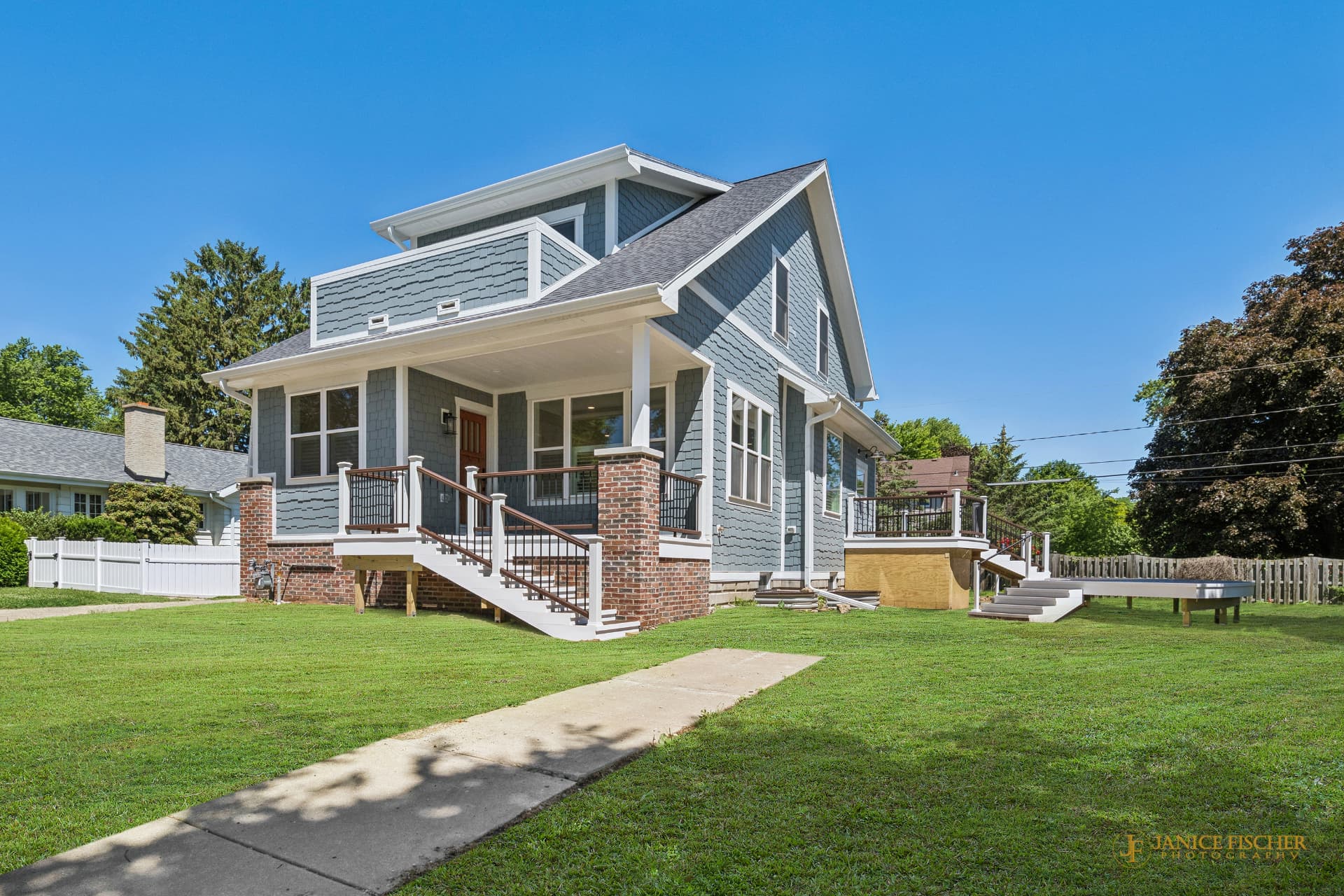 Blue shingle-sided custom home exterior with covered front porch and brick porch columns