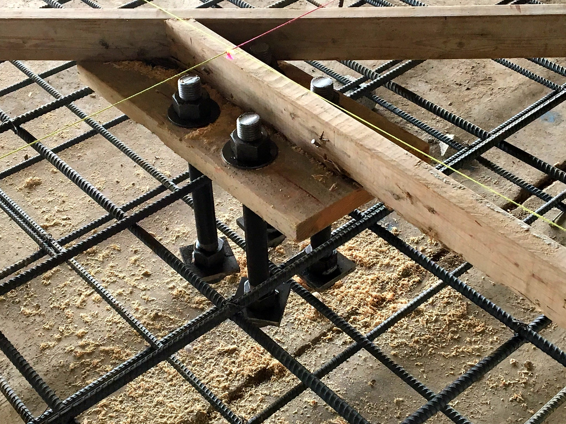 Anchor bolts and reinforcing steel set in a wood template before a foundation pour on an M3 Builders site