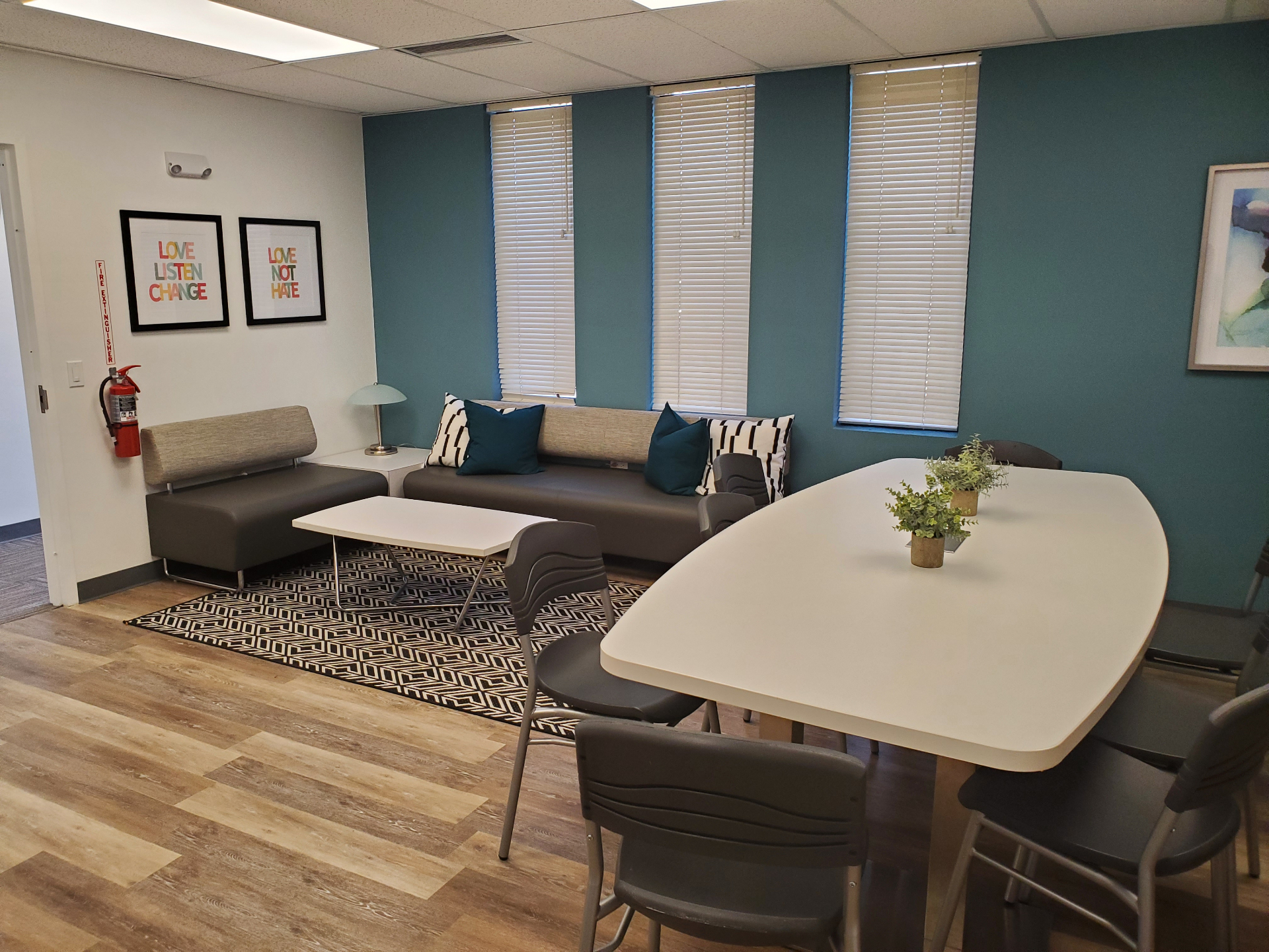 Community room with teal accent wall, sofa lounge area, and white meeting table