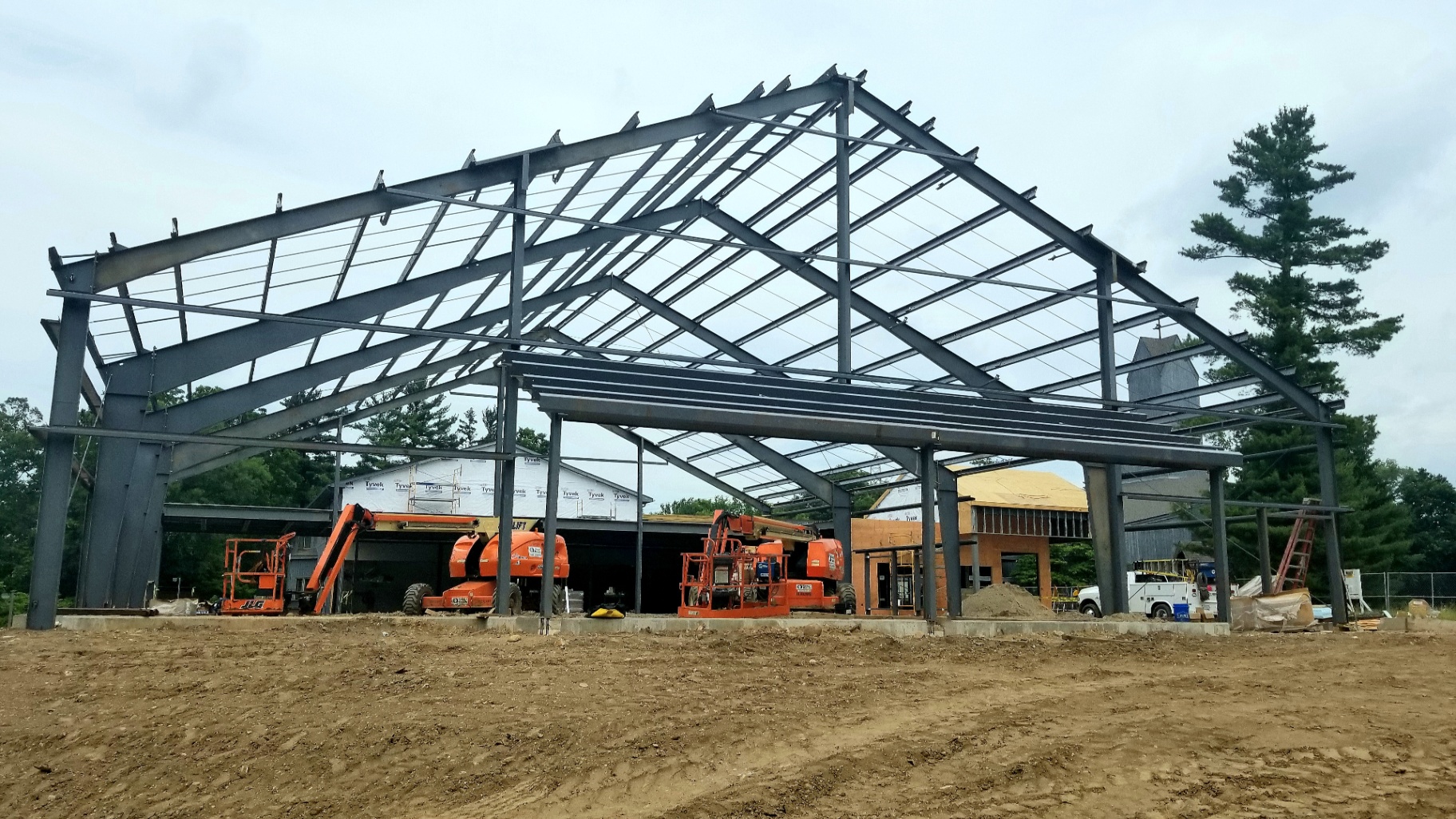 Structural steel building frame with roof purlins under construction and lifts on site